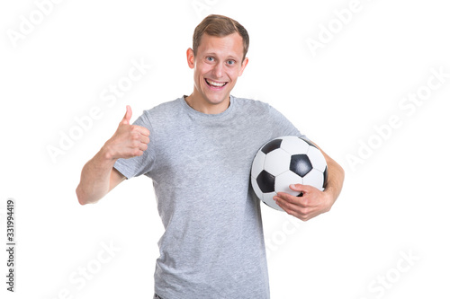 Football is a great game! Young happy man with a soccer ball in his hands shows a thumb up, isolated on a white background and looks at the camera.