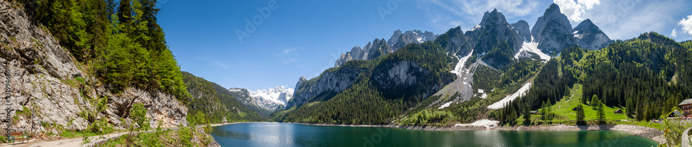 Famous Lake Gosau and Gosaukamm with Mount Dachstein. Spring is here! The snow is melting and spring brings the luscious green back to nature.  The sun is about to hide behind the high peaks.