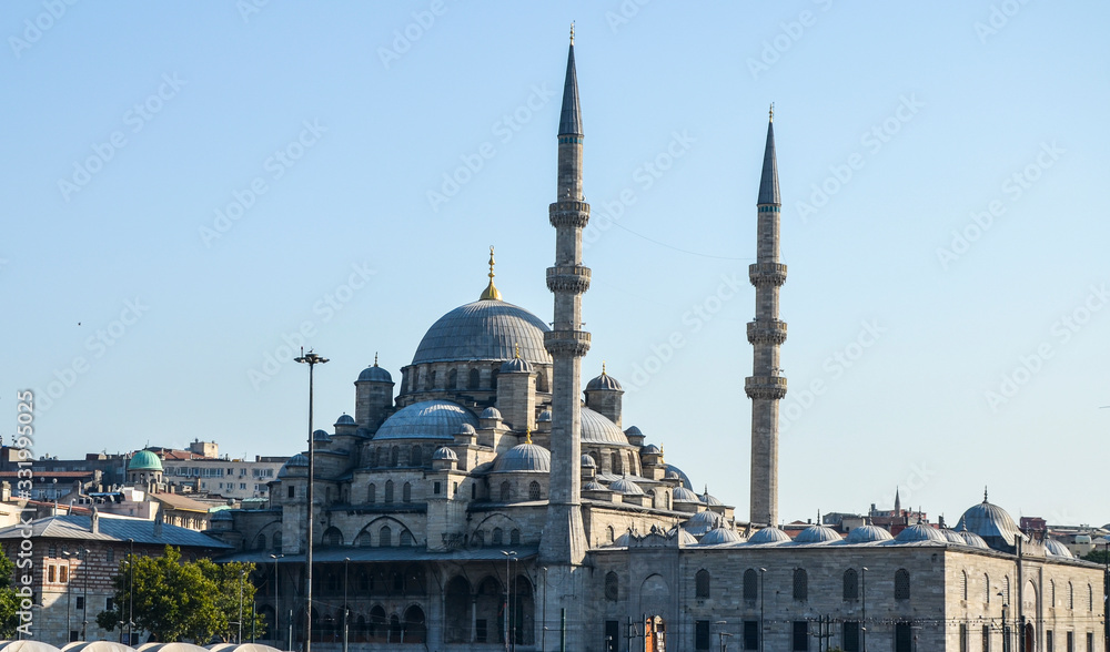  Domes and minaret of new mosque (Yeni Camii) view from Golden Horn, with clear blue sky behind. Istanbul, Turkey.