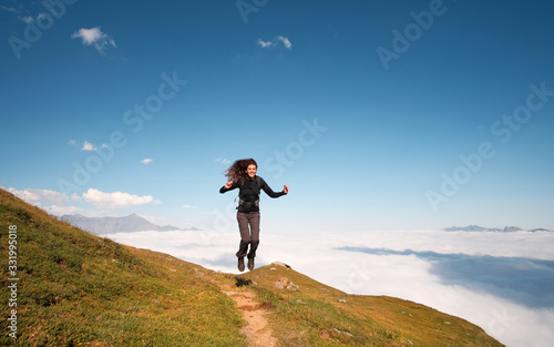 young woman jumping on the top of mountain