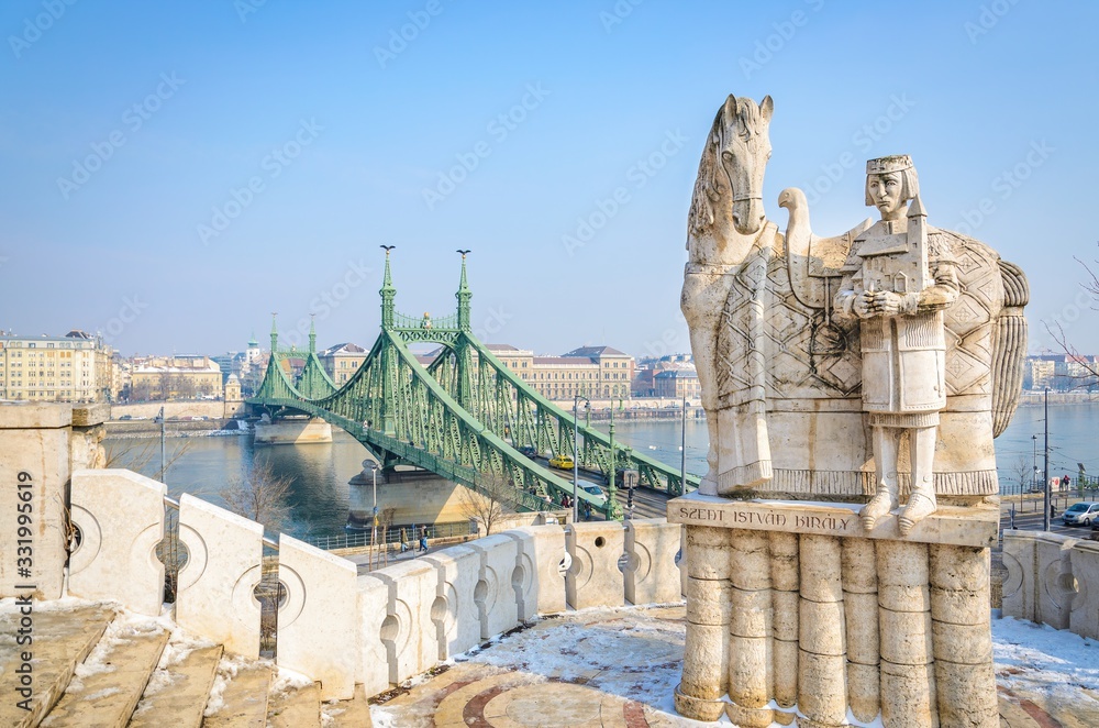 Fototapeta premium The famous statue of King Saint Stephen with his horse and the Liberty bridge on a sunny winter day in Budapest Hungary
