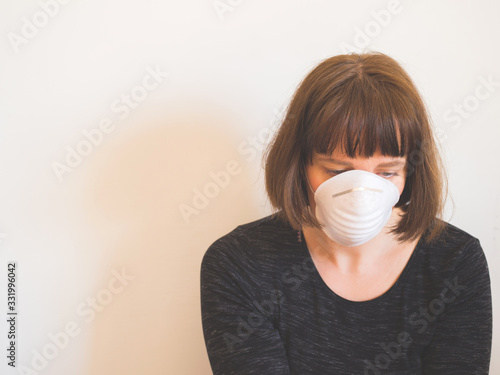 Frustrated caucasian young woman wearing face mask during Coronavirus pandemic quarantine staying home. photo