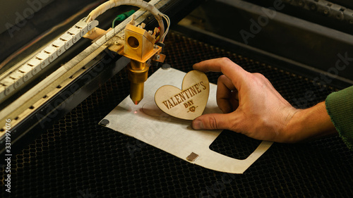 Laser cutting beam high precision on a plywood sheet. Modern technology of wood cutting. laser cut wooden 3d symbol of valentine's day. Industrial laser engraving. CNC laser. Masterclass, workshop