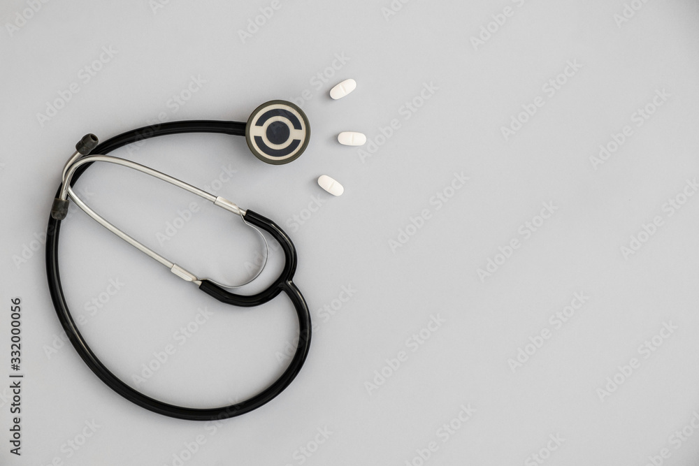 Flat lay composition with medical supplies on grey background. Space for text, minimalist image of stethoscope with paracetamol pills. Flat lay composition with medical supplies on grey background. Space for text, minimalist image of stethoscope with paracetamol pills.