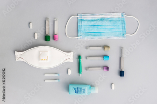 Flat lay composition of trusted medical supplies, medicine. Gray minimalist background with colored test tube, inyection and and mask