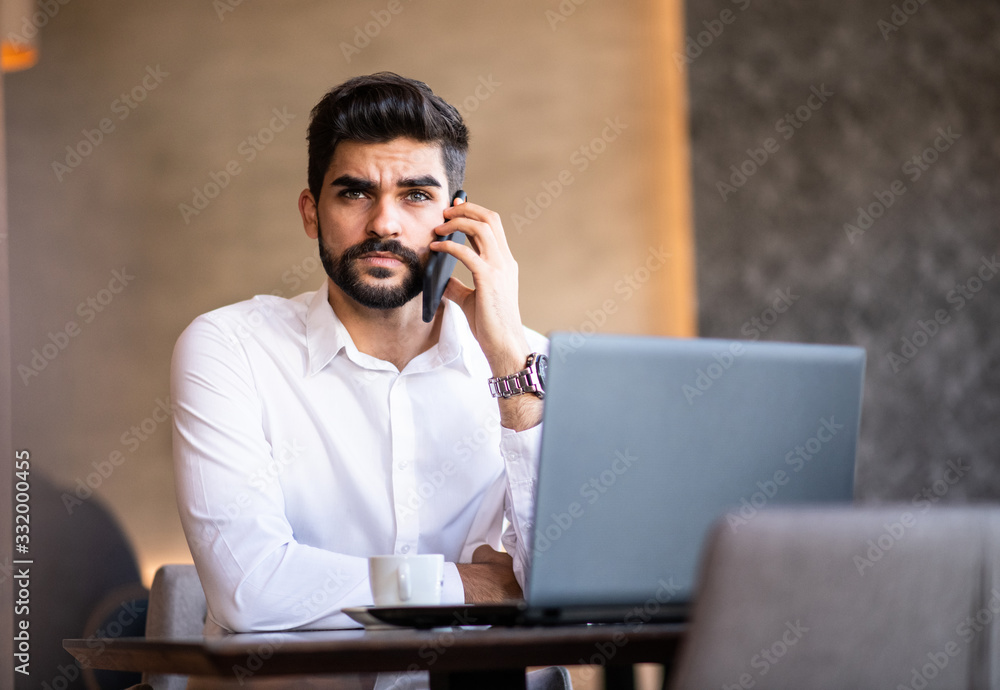 Businessman seriously talking on the phone looking at the camera. Businessman seriously talking on the phone looking at the camera.