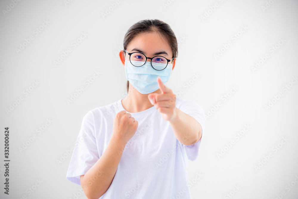Portrait Asian young woman wear a mask to protect against Coronavirus, girl raise fist and finger encourage fight contagious disease concept stop virus Covid 19 outbreak to victor on white background Portrait Asian young woman wear a mask to protect against Coronavirus, girl raise fist and finger encourage fight contagious disease concept stop virus Covid 19 outbreak to victor on white background
