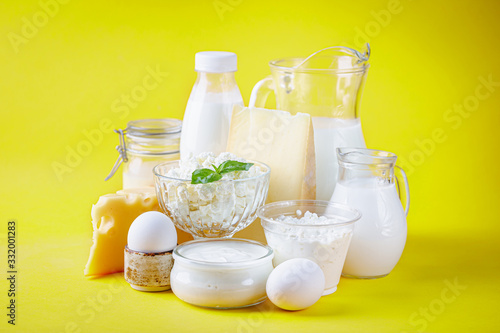 Fresh dairy products, milk, cottage cheese, eggs, yogurt, sour cream and butter on yellow background