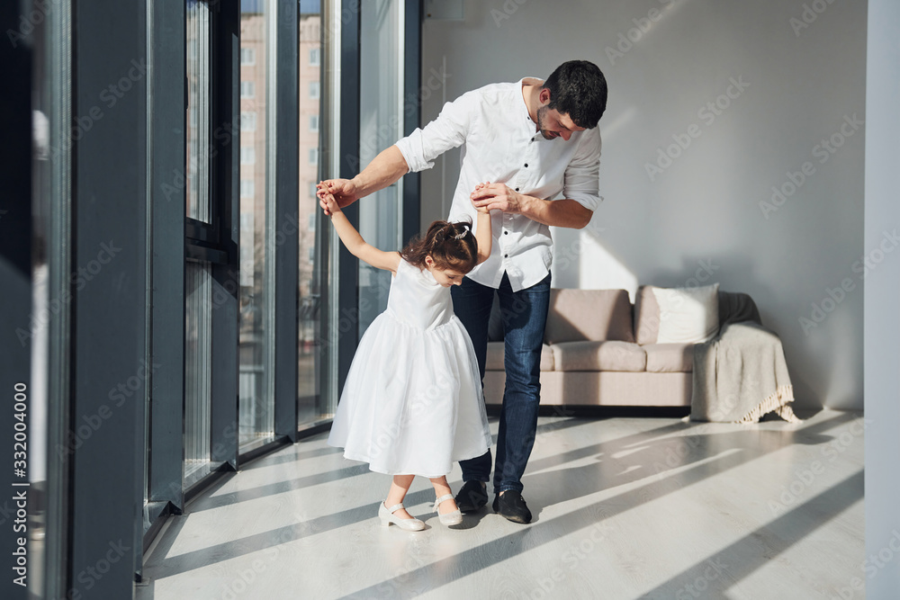 Fototapeta premium Happy father with his daughter in dress learning how to dance at home together