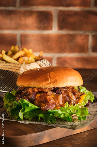 Burger with beef and caramelized onions on a wooden board. Cheeseburger with onion and beef. Juicy Delicious Homemade Burger.