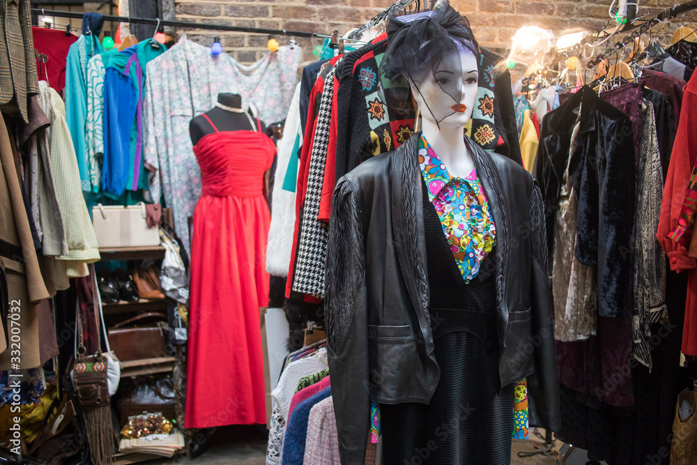 Spitalfields flea market. Mannequin in a cocktail dress and a hat with a veil on the background next to clothes