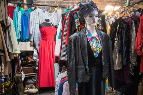 Spitalfields flea market. Mannequin in a cocktail dress and a hat with a veil on the background next to clothes
