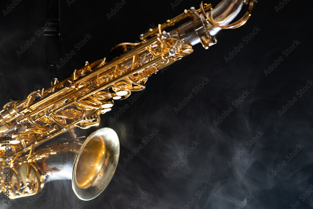 Fototapeta premium Golden shiny alto saxophone on black background with smoke. copy space