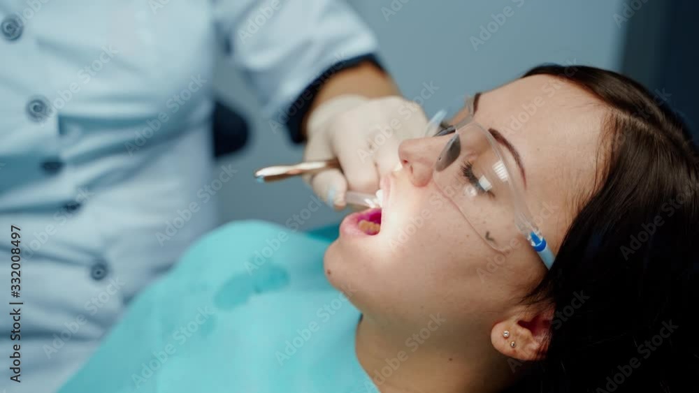 Dentist working with patient. Female dentist in uniform and gloves using dental instruments Dentist working with patient. Female dentist in uniform and gloves using dental instruments
