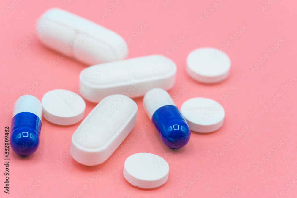Various white and blue pills on pink background with copy space. Different medical drugs . Various white and blue pills on pink background with copy space. Different medical drugs .