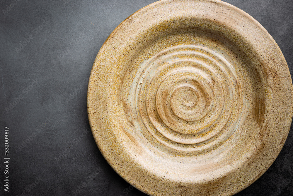 Empty pottery plate on black background, top view Empty pottery plate on black background, top view