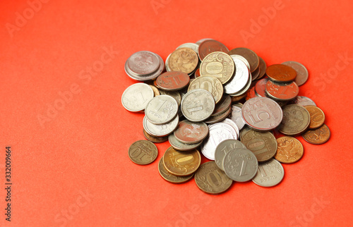 A pile of metal coins on a red background. A lot of Russian rubles. Selective focus. Home savings. Copy space