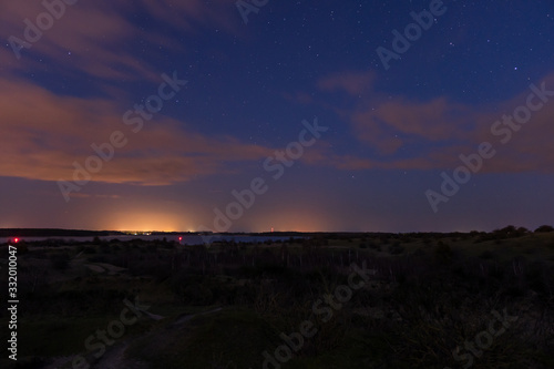 Landscape shot of the night sky with stars and clouds captured on the hilly peninsula Devin near Stralsund and Ruegen with the ocean in the background