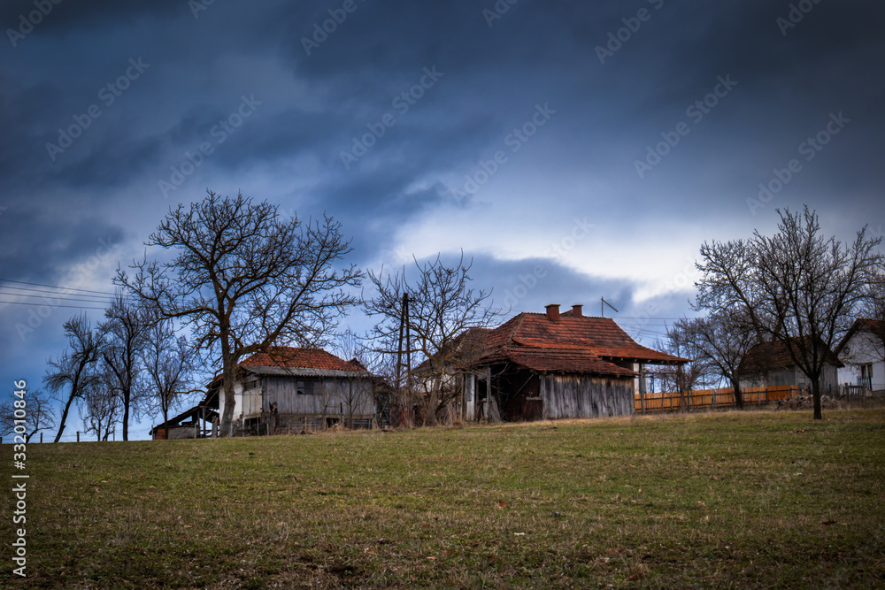 Obraz premium Old houses in the village, cloudy winter sunset