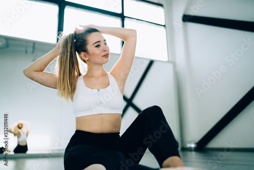Athletic woman arranging hair in fitness studio