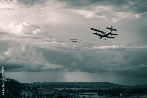 Two old biplanes flying in the stormy sky of Budapest, Hungary