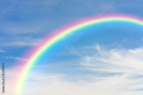 Rainbow and blue sky with clouds background © pushish images