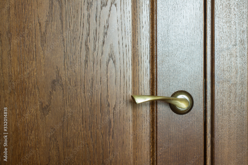 Fragment of a wooden brown textured door with a metal door handle close-up with copy space. Concept: hygiene, coronavirus Fragment of a wooden brown textured door with a metal door handle close-up with copy space. Concept: hygiene, coronavirus