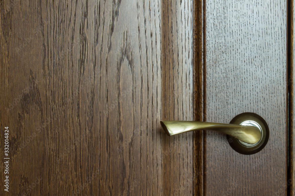 Fragment of a wooden brown textured door with a metal door handle close-up with copy space. Concept: hygiene, coronavirus Fragment of a wooden brown textured door with a metal door handle close-up with copy space. Concept: hygiene, coronavirus