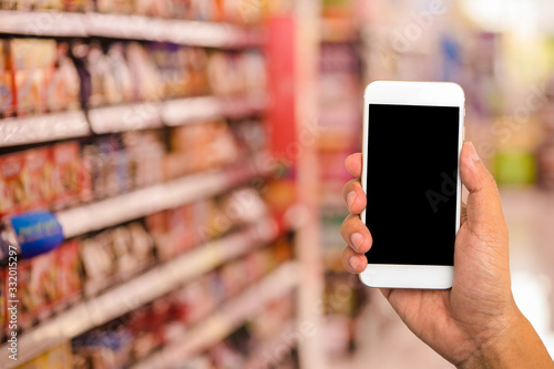 Hand hold blank smartphone on blur supermarket background