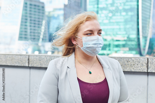 blonde girl stay at street near business center in a medical mask