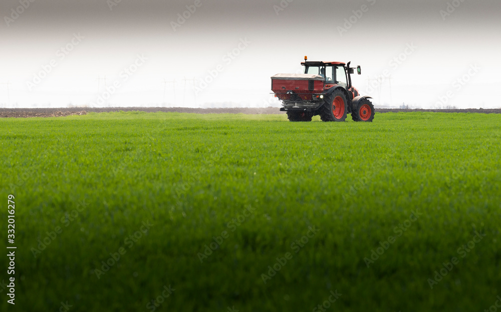 Tractor spreading artificial fertilizers in field Tractor spreading artificial fertilizers in field