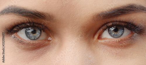 Close-up of open female gray eyes with casual makeup looking camera