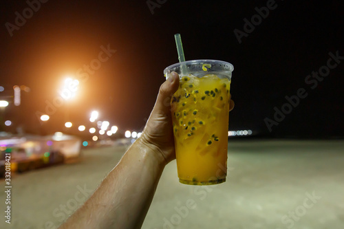 Brazilian caipirinha cocktail in a disposable glass on a night street. photo