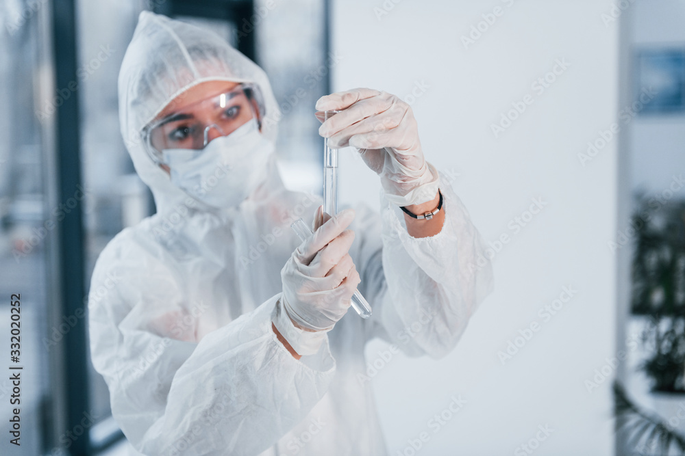 Holds test tubes. Portrait of female doctor scientist in lab coat, defensive eyewear and mask Holds test tubes. Portrait of female doctor scientist in lab coat, defensive eyewear and mask