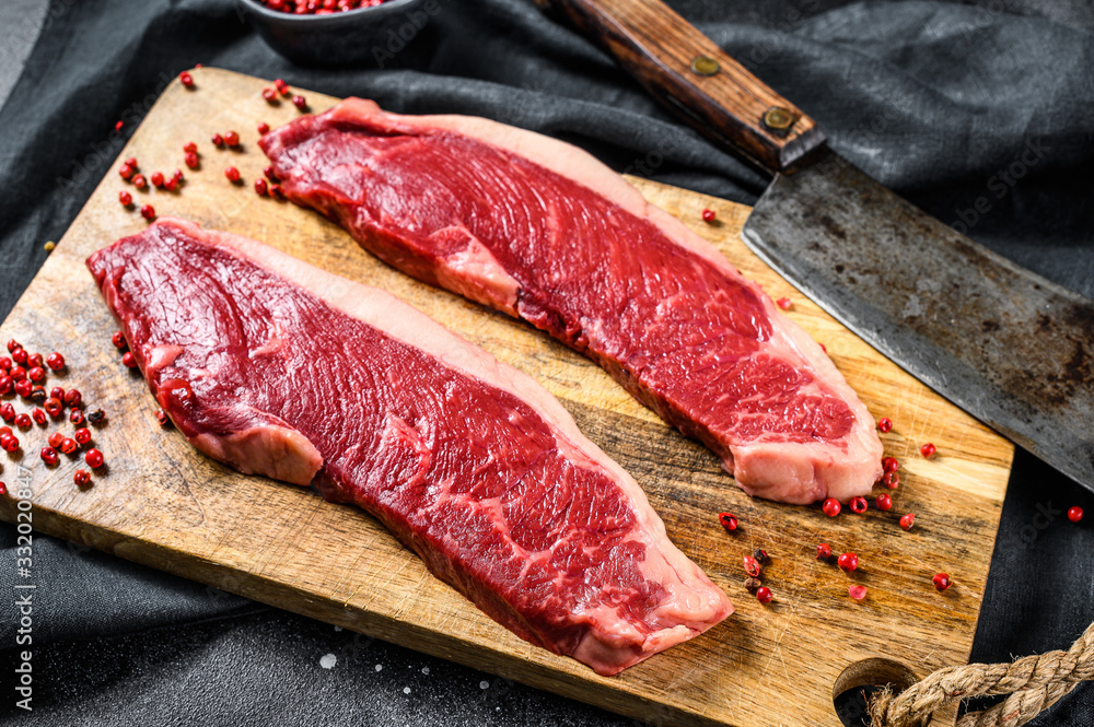 Strip loin steak on a cutting Board. Organic beef meat. Black background. Top view