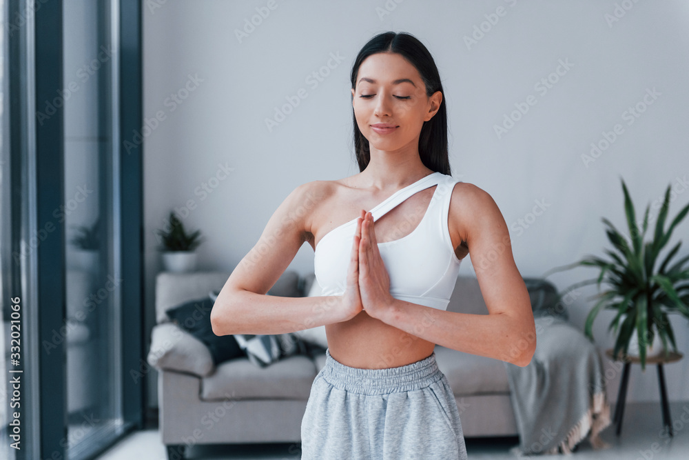 Does yoga exercises. Young woman with slim body shape in sportswear have fitness day indoors at home