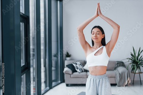 Does yoga exercises. Young woman with slim body shape in sportswear have fitness day indoors at home