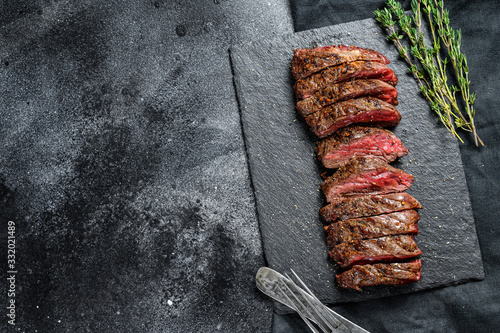 Grilled roasting rare sliced vegas strip steak. Marble meat beef. Black background. Top view. Copy space