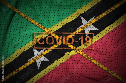 Saint Kitts and Nevis flag and Covid-19 stamp with orange quarantine border tape cross. Coronavirus or 2019-nCov virus concept photo