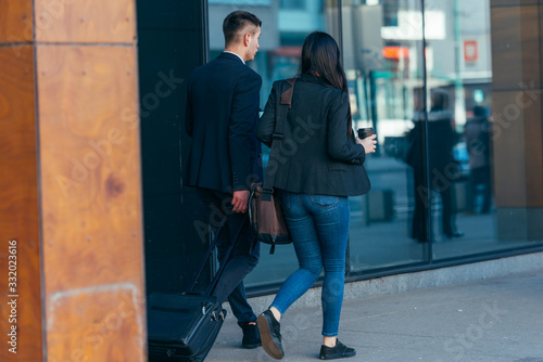 Business couple ( colleagues ) walking along the futuristic modern station (airport) while drinking coffee and talking to each other.