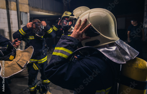 Group of firefighters standing inside the fire brigade wearing helmet and protective uniform © qunica.com