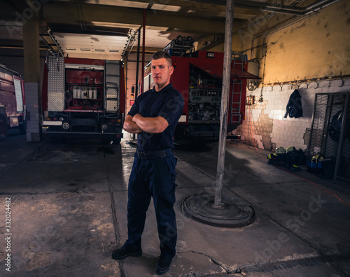Portrait of confident young fireman standing inside the fire departmant