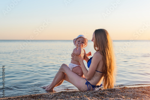Fotografía Young beautiful mother in swimsuit with the baby on beach