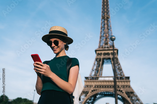 Happy Caucasian tourist in straw hat and trendy sunglasses writing text for sharing content publication about romantic French vacations, smiling blogger enjoying solo journey for exploring France © BullRun
