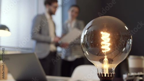 Business people discussing creative strategies and lit lamp photo