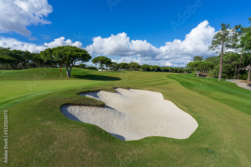 Beautiful, empty golf course with blue sky and green grass with tree