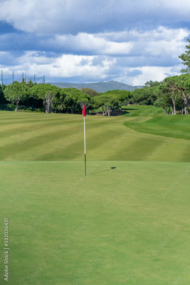 Obraz premium Beautiful golf course in summer with red golf flag and green grass