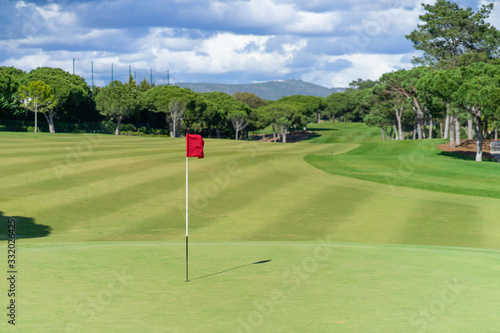 Beautiful golf course in summer with red golf flag and green grass