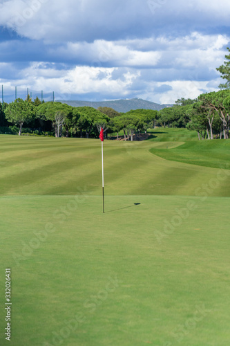 Beautiful golf course in summer with red golf flag and green grass