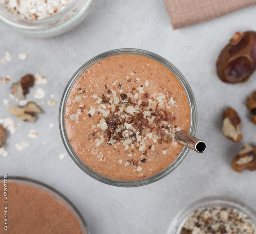 Smoothie from dates, nuts, chocolate in a glass on a light gray background top view Smoothie from dates, nuts, chocolate in a glass on a light gray background top view